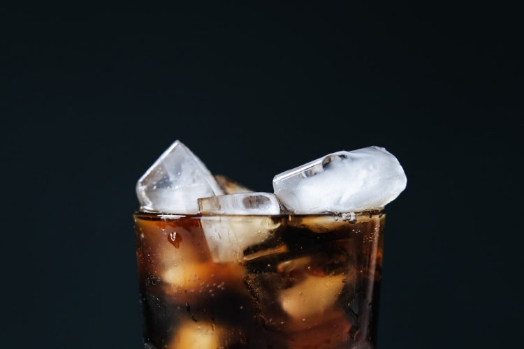 Tall glass of cola beverage with ice cubes