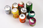 Nine different soda cans in assorted colors on white table