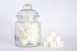 Sugar cubes in stack beside glass sugar jar