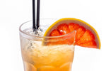 Tall glass of orange soda with two black soda straws and orange slice garnish
