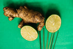 Ginger root beside two lime slices on bright green placemat