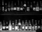 Assorted flavors and brands of glass soda bottles lined on two shelves