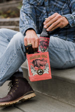 Man in flannel shirt on concrete stoop pulling Colorado Cola bottle from four-pack